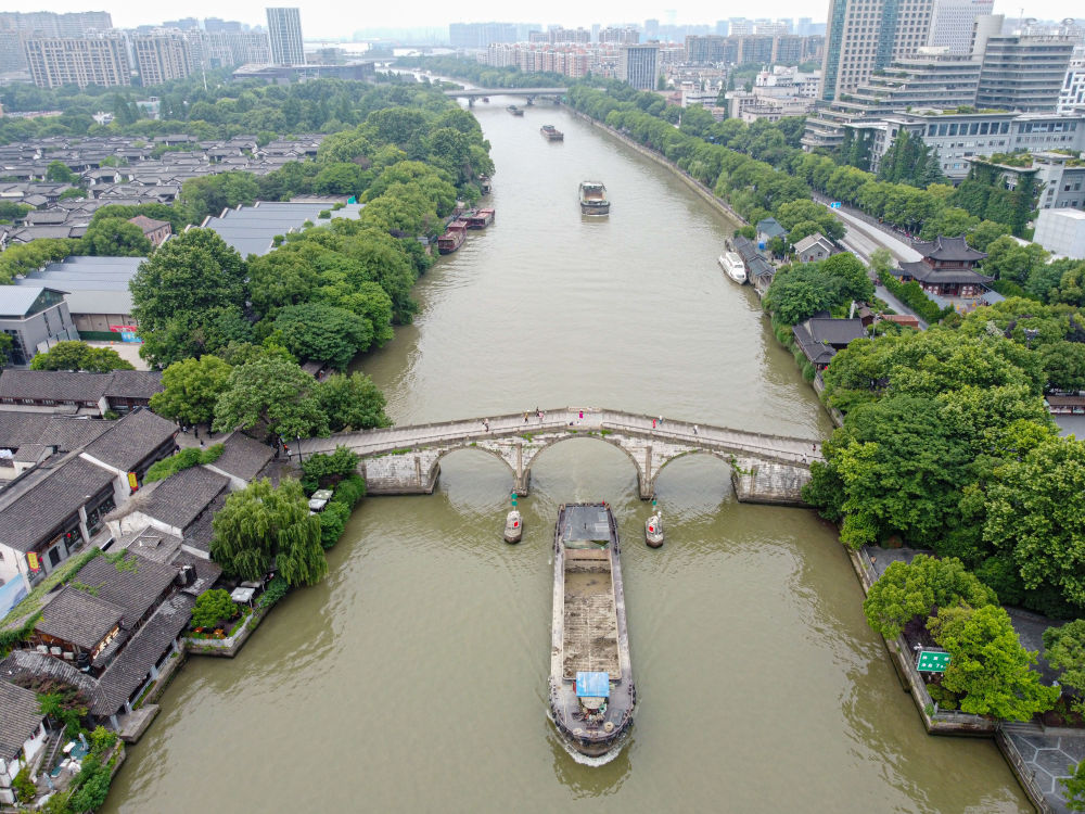 5月27日，一艘貨船駛過(guò)京杭大運(yùn)河南端標(biāo)志建筑杭州拱宸橋。(無(wú)人機(jī)照片)新華社記者江漢 攝