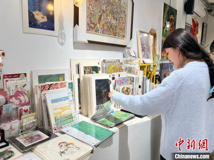 圖為藝術(shù)品商店內(nèi)，顧客挑選插畫作品?！＄婌?攝