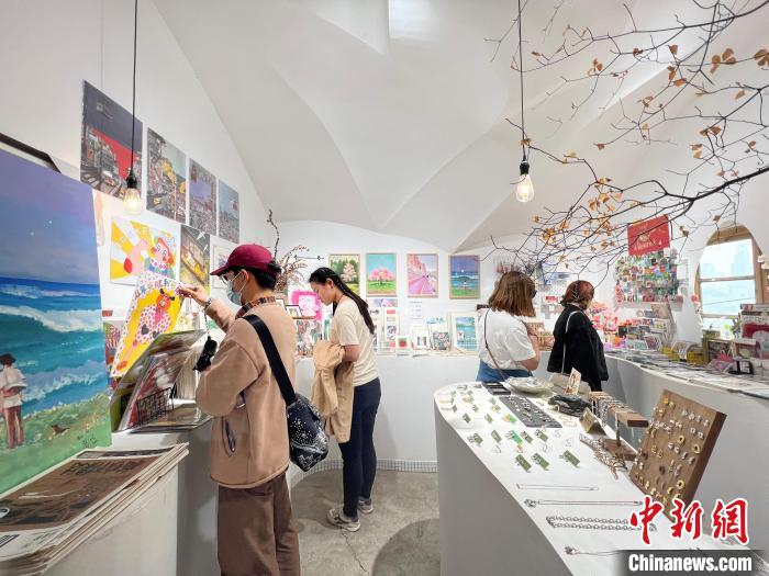 圖為藝術(shù)品商店內(nèi)，顧客挑選插畫作品?！＄婌?攝