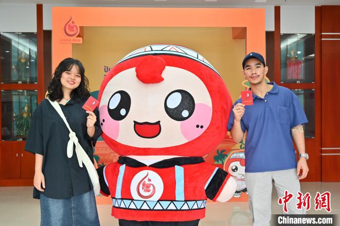 圖為泰國(guó)留學(xué)生手持獻(xiàn)血證與人偶合影?！∮峋?攝