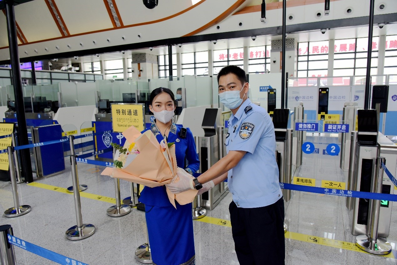 磨憨出入境邊防檢查站民警為中老鐵路第100萬名出入境旅客，D888次國際旅客列車?yán)蠐爰藙?wù)員森達(dá)拉·妮緹婭（Sengdala Nitiya），送上鮮花。黃遠(yuǎn)飛 攝