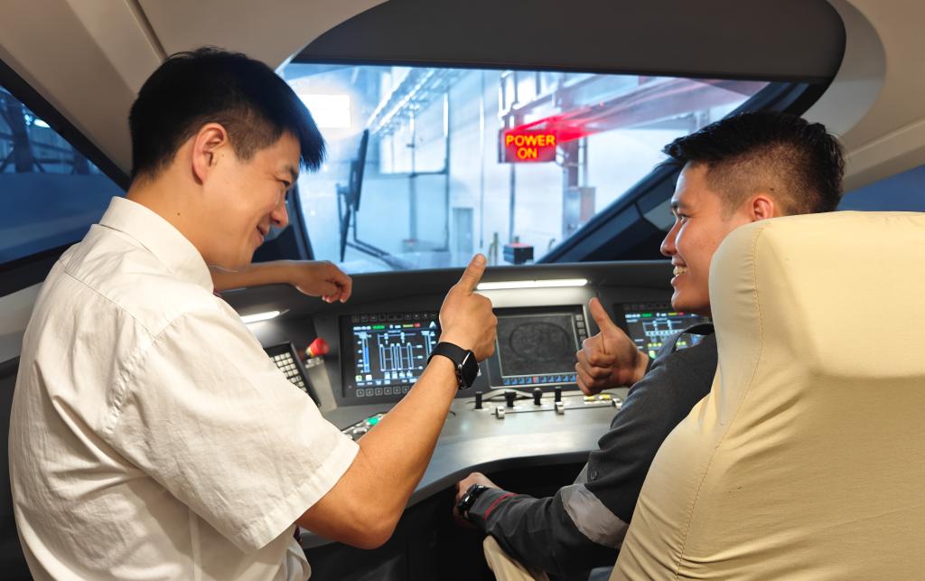 8月25日，在印度尼西亞萬隆的雅萬高鐵德卡魯爾動(dòng)車所內(nèi)，中國師傅穆振（左）在向印尼火車司機(jī)塞蒂亞萬講解動(dòng)車組出庫前的上電作業(yè)。