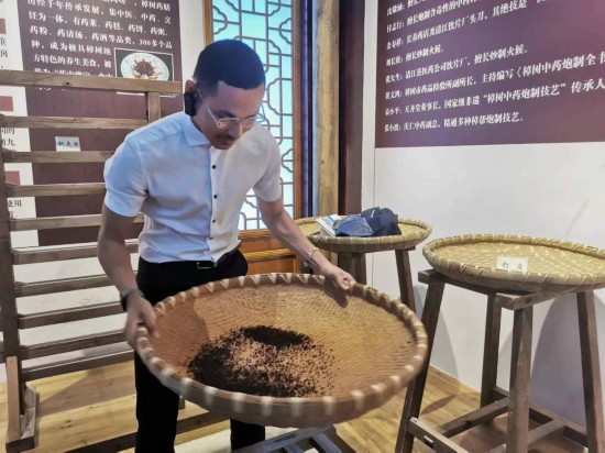 2023“一帶一路”媒體合作論壇聯(lián)合采訪團團員在非遺文化展示館體驗中藥炮制技藝。（本報記者 黃超攝）