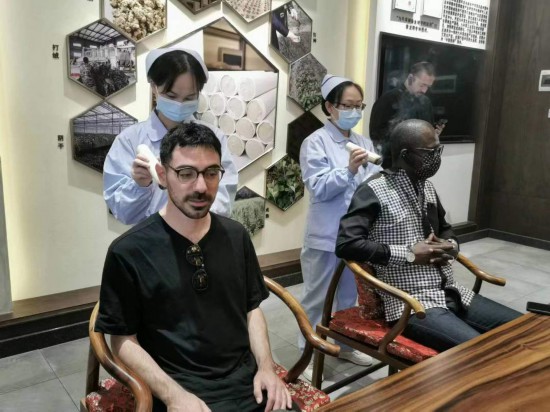 2023“一帶一路”媒體合作論壇聯(lián)合采訪團團員在九牛草展示館體驗艾灸。（本報記者 黃超攝）