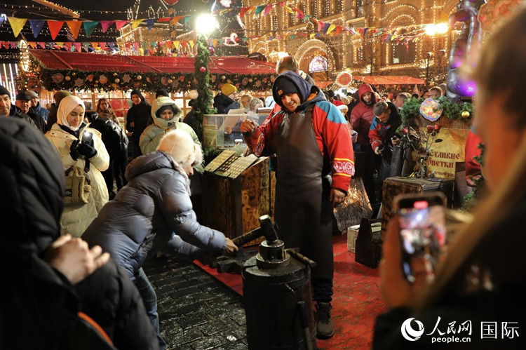 游客在新年集市上體驗(yàn)制作紀(jì)念幣。人民網(wǎng)記者 隋鑫攝