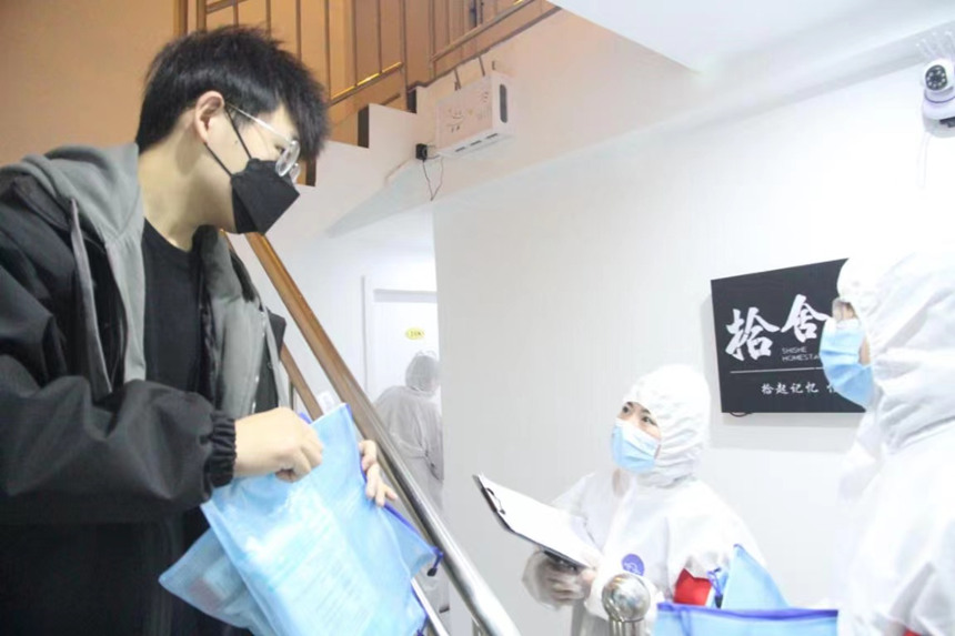 社區(qū)工作人員和志愿者身穿防護(hù)服上門(mén)送馬應(yīng)龍大健康防疫包。徐帥攝