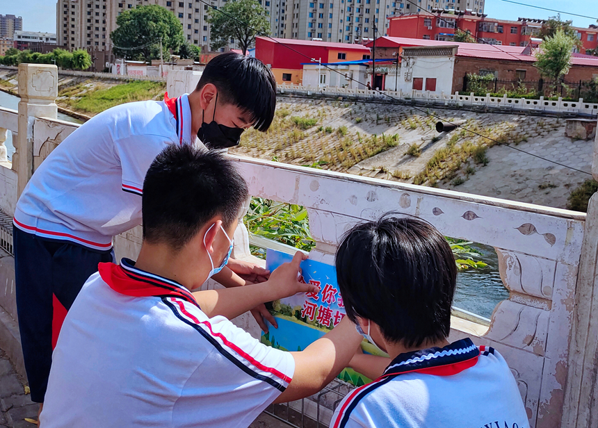徐水小學(xué)學(xué)雷鋒志愿者在瀑河河邊張貼防溺水警示標(biāo)語。 徐水區(qū)委宣傳部供圖