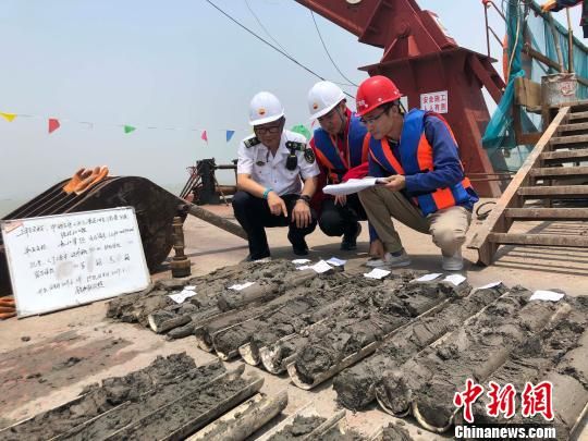 圖為勘察設(shè)計(jì)人員與海事局工作人員查看巖芯情況。　魏震 攝