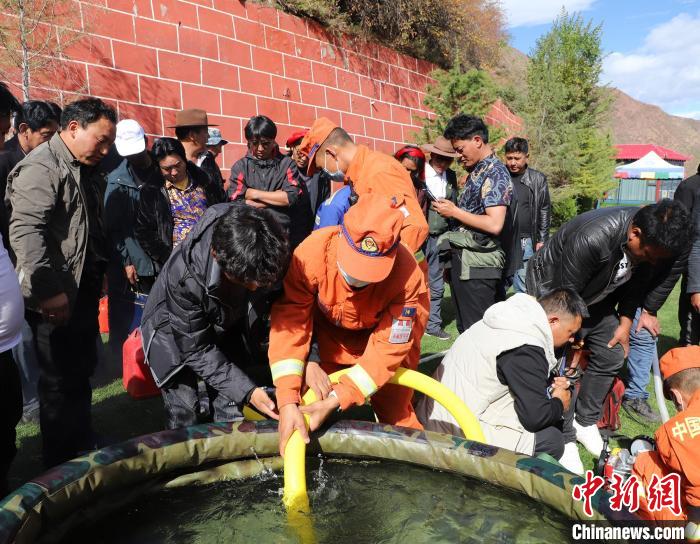 圖為森林消防員為護(hù)林員講解滅火裝備的使用方法?！〔际猩窒乐ш?供圖