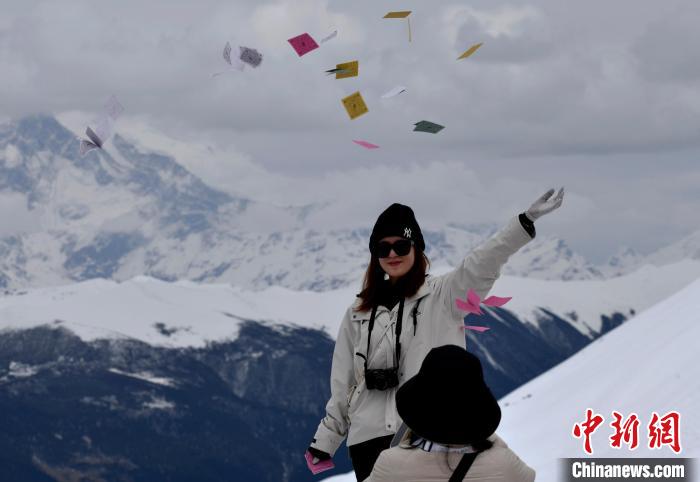 圖為5月14日，游客在西藏林芝色季拉山觀景臺(tái)拋灑“隆達(dá)”(風(fēng)馬旗，藏族民眾的一種祈福方式)?！±盍?攝