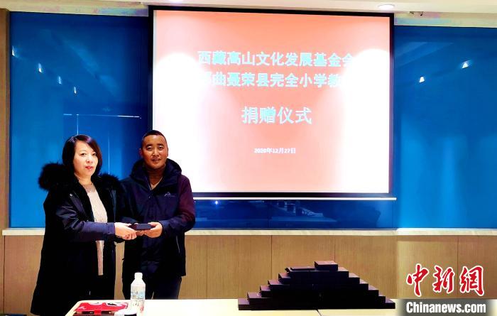 圖為西藏高山文化發(fā)展基金會(huì)理事長(zhǎng)溫麗向聶榮縣完全小學(xué)負(fù)責(zé)人捐助儀器?！∮谫e 攝