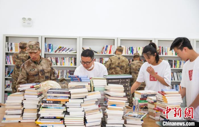 圖為志愿者們和邊防戰(zhàn)士整理圖書?！詵| 攝