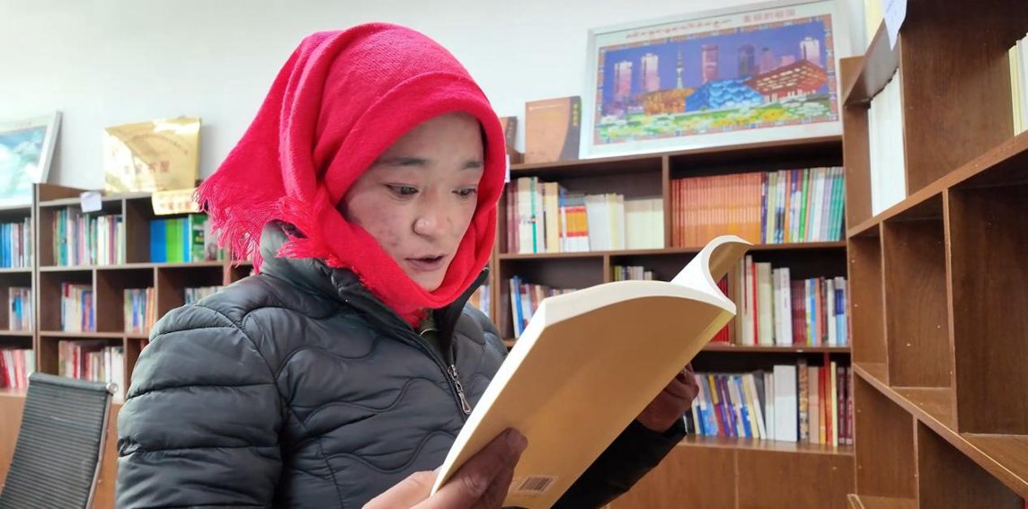 一名婦女正在認(rèn)真閱讀書籍。申扎縣融媒體中心供圖