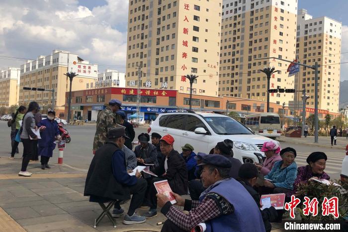 圖為會(huì)澤縣城易地扶貧搬遷安置點(diǎn)內(nèi)，老人們聚在廣場上聊天，身后是他們的新家。　繆超 攝