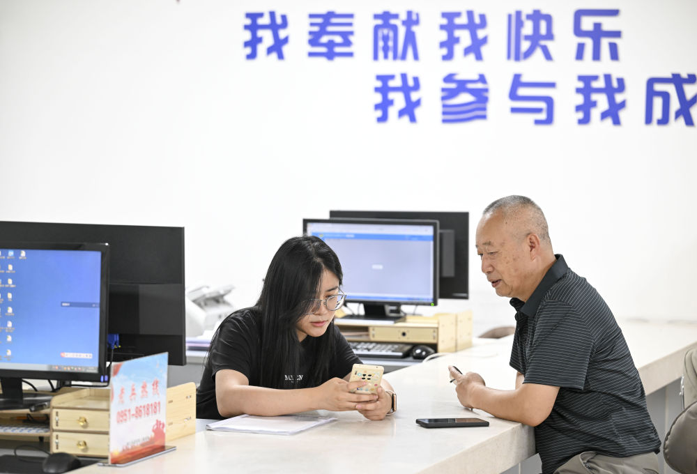 2024年6月20日，在寧夏銀川市金鳳區(qū)長城花園社區(qū)黨群服務(wù)中心，工作人員幫助居民辦理業(yè)務(wù)。圖片來源 新華社