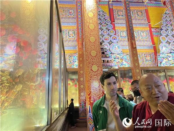 7月25日，省級(jí)非物質(zhì)文化遺產(chǎn)項(xiàng)目塔爾寺酥油花的代表性傳承人朋措堅(jiān)參（右）在塔爾寺酥油花館講解酥油花的制作過程。人民網(wǎng) 謝瑩攝