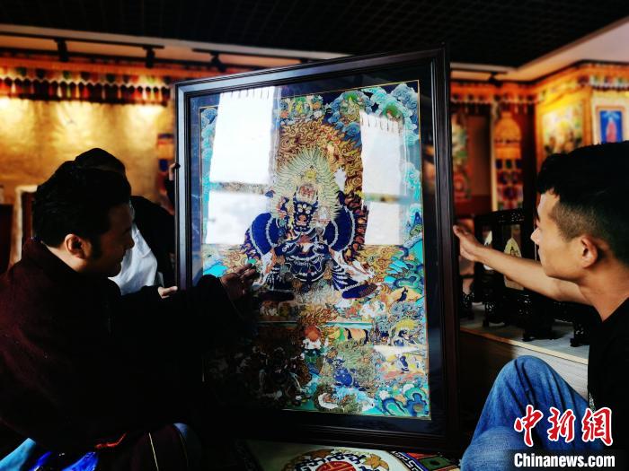 圖為久美尖措(左)與徒弟們展示唐卡作品。　張?zhí)砀?攝