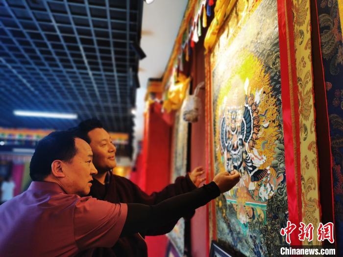 圖為久美尖措展示唐卡作品?！?zhí)砀?攝