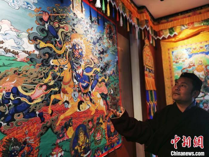 圖為久美尖措展示唐卡作品?！?zhí)砀?攝
