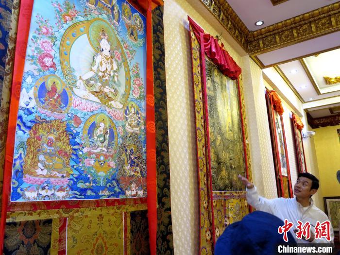 圖為完德尖措展示熱貢龍樹畫苑內(nèi)的唐卡?！?zhí)砀?攝