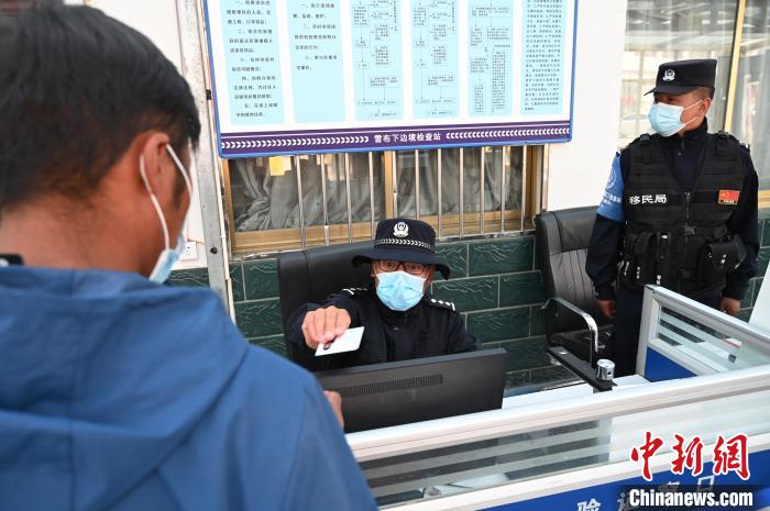 圖為移民管理警察登記完身份信息后將證件歸還給行人?！≮w朗 攝