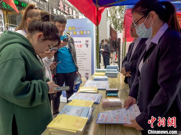 圖為工作人員正在向路過(guò)市民介紹國(guó)家反詐中心軟件的功能。　謝牧 攝