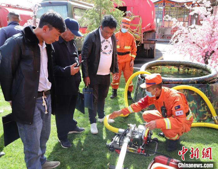 圖為森林消防員為護(hù)林員講解滅火裝備的使用方法?！〔际猩窒乐ш?duì) 供圖