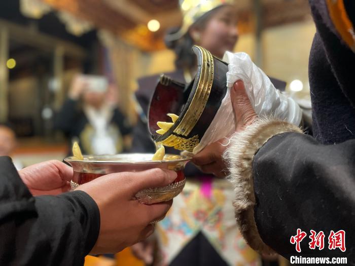 圖為主人在碗中斟滿青稞酒?！∪轿木?攝