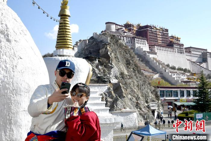 4月17日，游客身著藏式元素服裝在拉薩布達拉宮觀景臺拍照留念。　李林 攝
