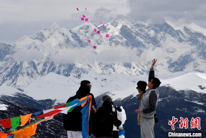 圖為5月14日，游客在西藏林芝色季拉山觀景臺(tái)拋灑“隆達(dá)”(風(fēng)馬旗，藏族民眾的一種祈福方式)。　李林 攝
