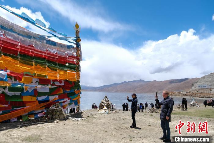 進(jìn)藏參訪嘉賓在羊湖畔拍攝經(jīng)幡?！〗w波 攝