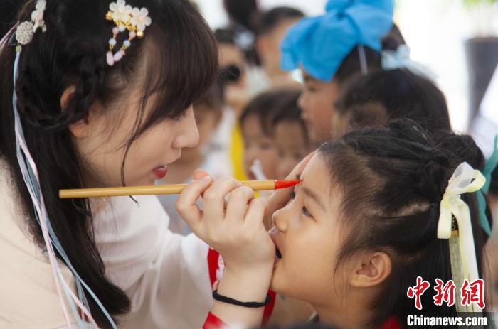 圖為老師在孩子們額頭上點(diǎn)上雄黃，驅(qū)邪辟禍?！《^生 攝